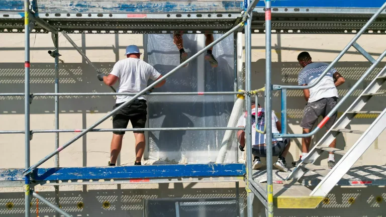 Referenz richardt.com, Handwerker auf einem eingerüsteten Gerüst arbeiten an der Fassadensanierung eines Gebäudes.