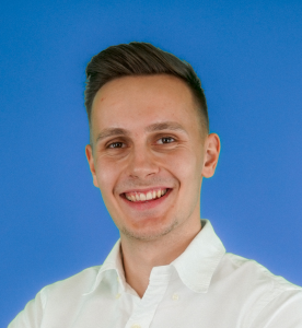 Porträt von Laurenz Reuber, Vertriebsberater bei GRZ Digital, vor blauem Hintergrund lächelnd.